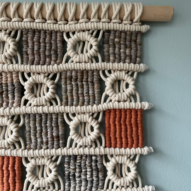 An ASTRL Fibres macrame wall taestry on a light blue background