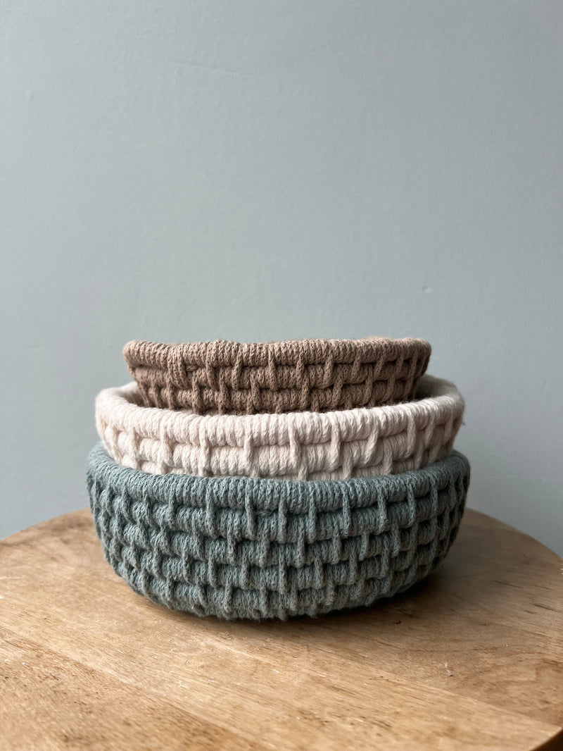 3 stacked fibre baskets in blue, white and taupe on a table with a light blue background