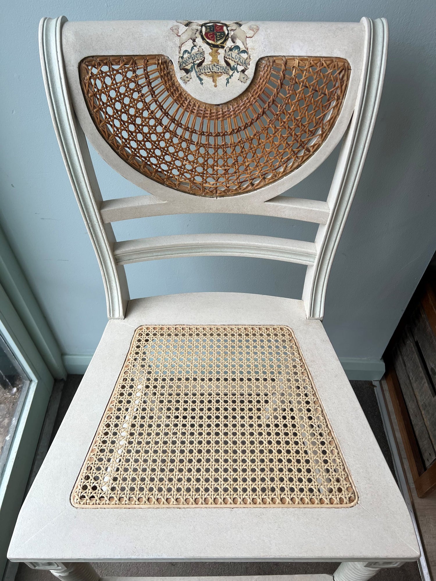 Clive Christian high back stool with woven cane seat against a light blue wall.