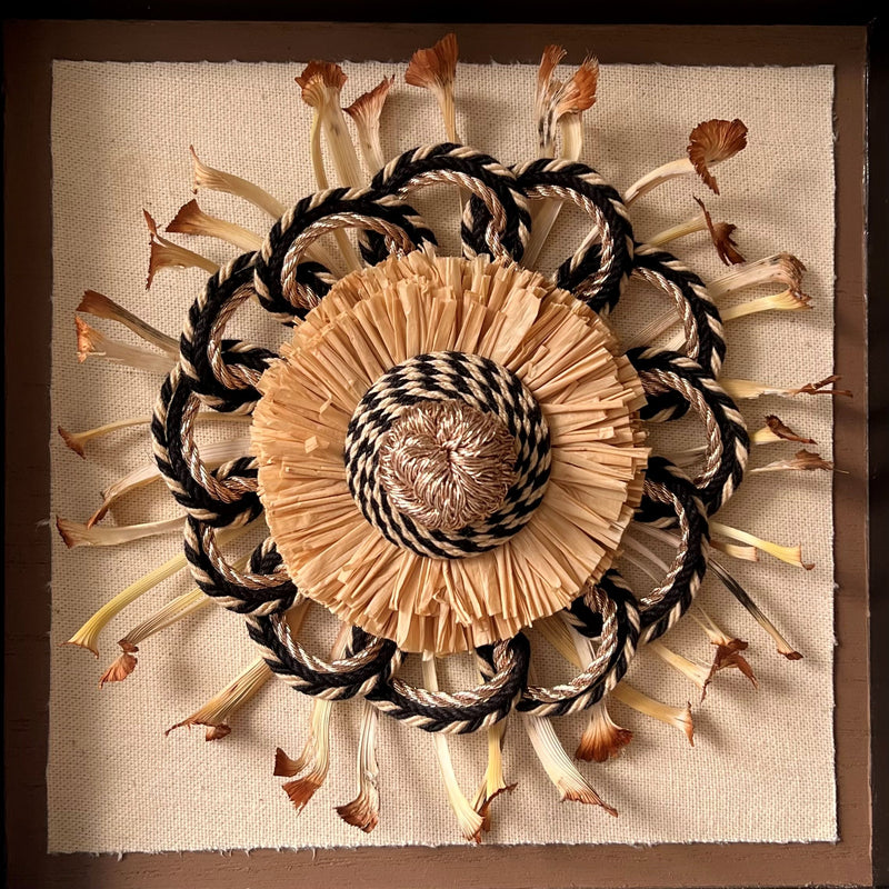 Close up of a black and gold passementerie rosette with natural materials on a linen background