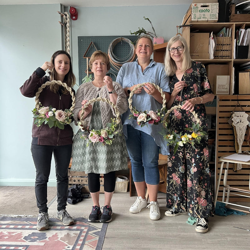Four women holding floral macramé wreaths in the ASTRL Fibres studio in Belfast.