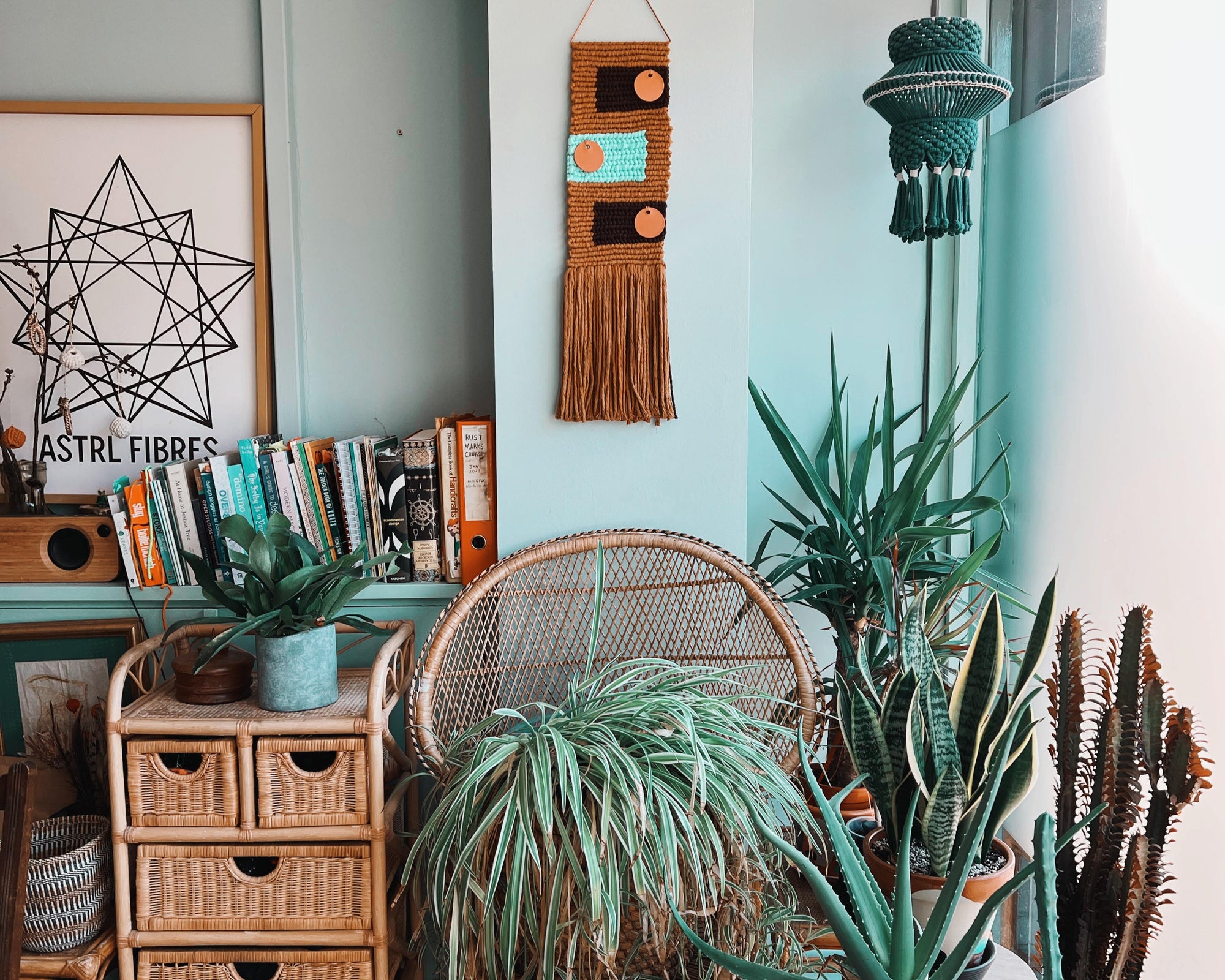 A bright room interior with wicker furniture, plants, and macramé wall art in a home craft studio setting