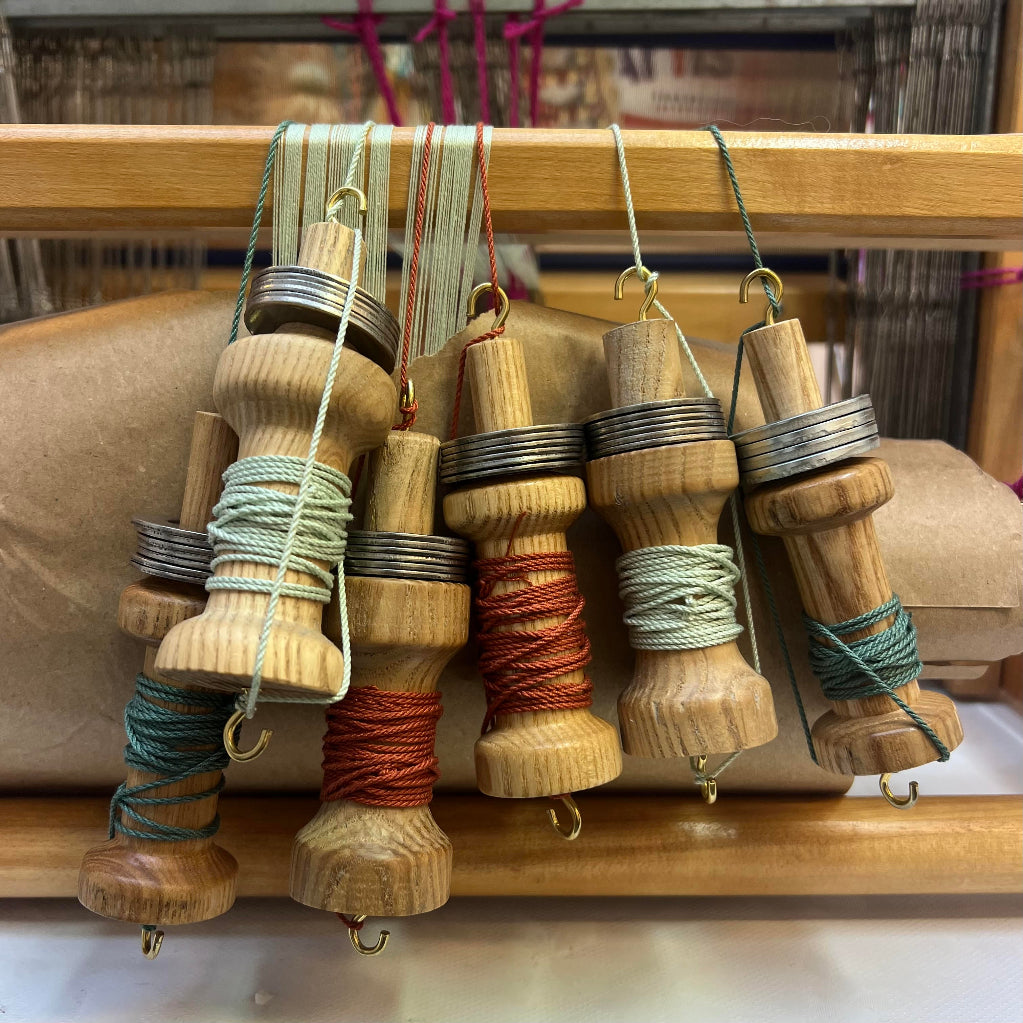 A bunch of colourful bespoke cords coiled on wooden spools