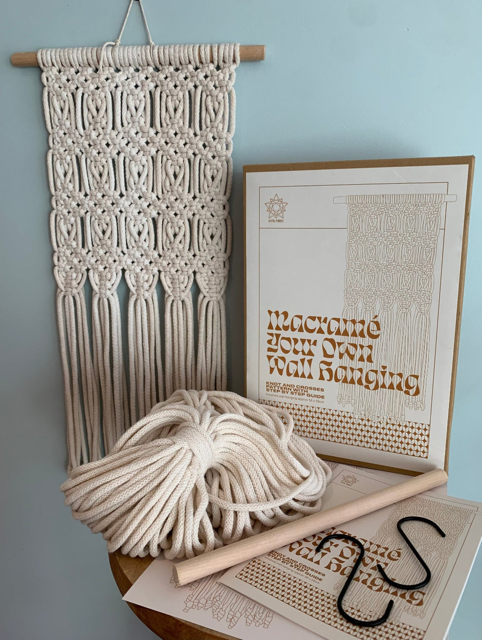 ASTRL Fibres Macrame Your Own Wall hanging kit with instructions and materials on a light blue background